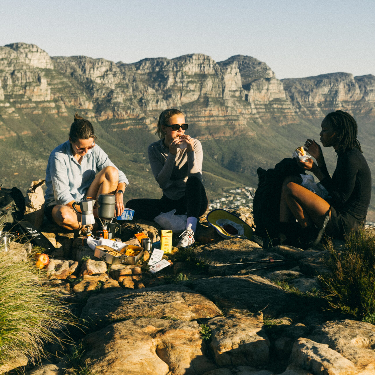 three female hikers enjoying food on top of mountain