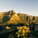three hikers standing on Lion's Head looking towards Table Mountain