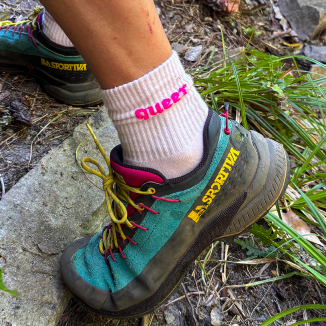 woman with hiking shoe and sock that says "queer"
