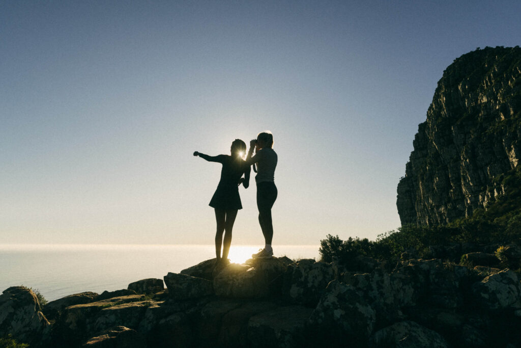 two hikers on the mountain looking out over the ocean